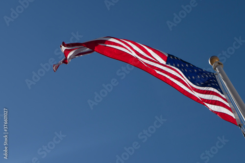 United States of American red whiote and blue flag blowing in the wind on a clear blue day shy photo