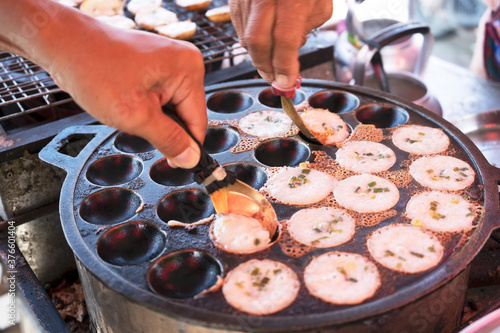 hands picking Knmcrk, made from coconut milk with sugar and flour. Native sweets Thai traditional dessert photo