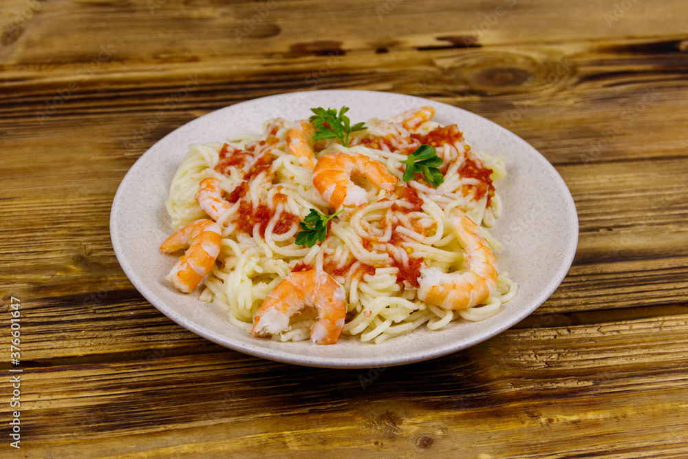 Spaghetti pasta with prawns, tomato sauce and parsley on wooden table Spaghetti pasta with prawns, tomato sauce and parsley on wooden table