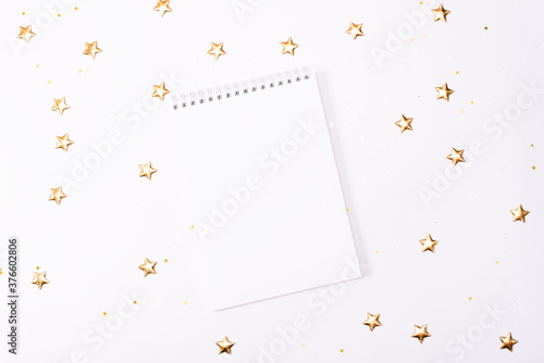 Top view of blank notebook on white wooden background with xmas decorations, copy space. Christmas background with notebook for wish list or to do list, red gift boxes, fir tree branches. Flat lay