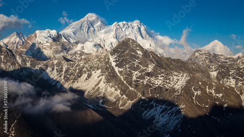 Mountains eight-thousanders of Everest region before sunset. Everest and Lhotse in the centre, Makalu on the right. Bright blue sky above with light clouds. Dark shadows below. photo