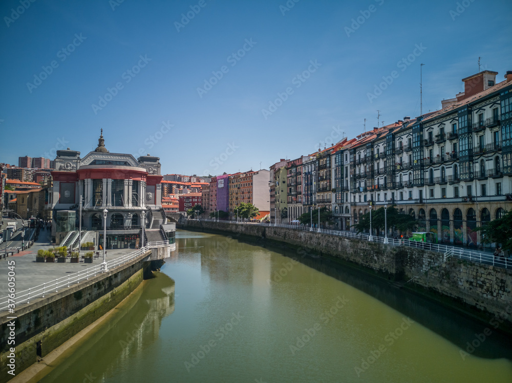 Cityscape of Bilbao, Spain, with the market hall beside the river Nervion with colorful buildings and a clear blue sky