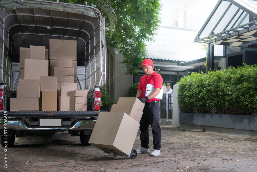 Asian delivery man in red uniform delivering parcel boxes to woman recipient at home