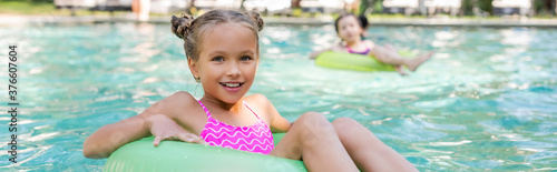 horizontal image of girl looking at camera while floating in pool on swim ring