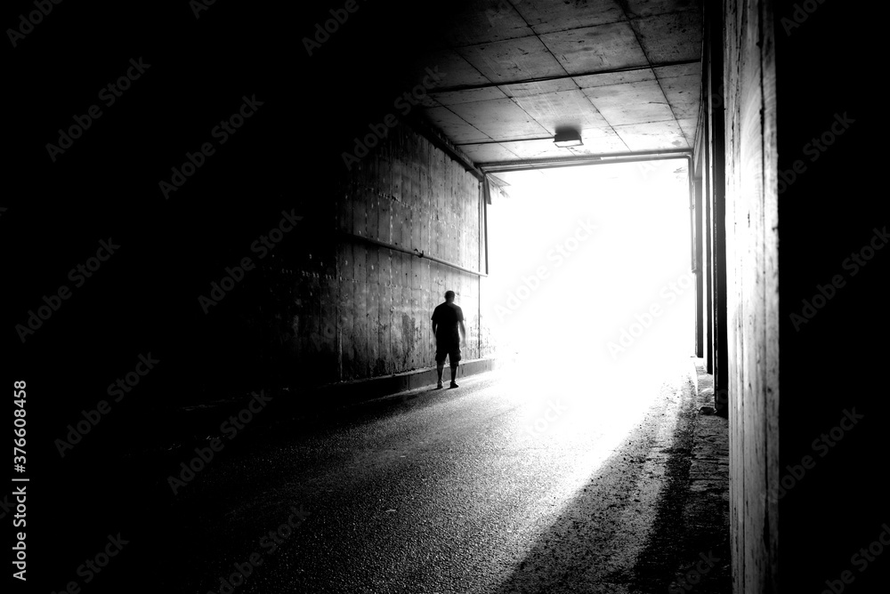 Obraz premium Moving silhouette of a young man in a dark tunnel in blur.