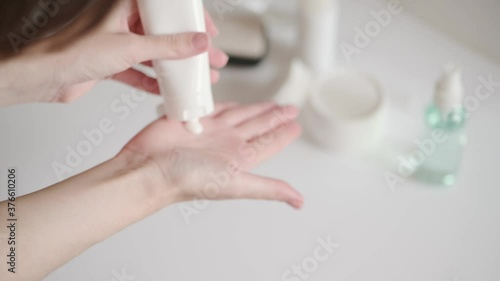 Wallpaper Mural The woman takes a plastic tube of cream from the white table and smears her hands. Hand skin care at home. Moisturizing lotion with vitamins, body care. Cosmetic beauty skincare product. Torontodigital.ca