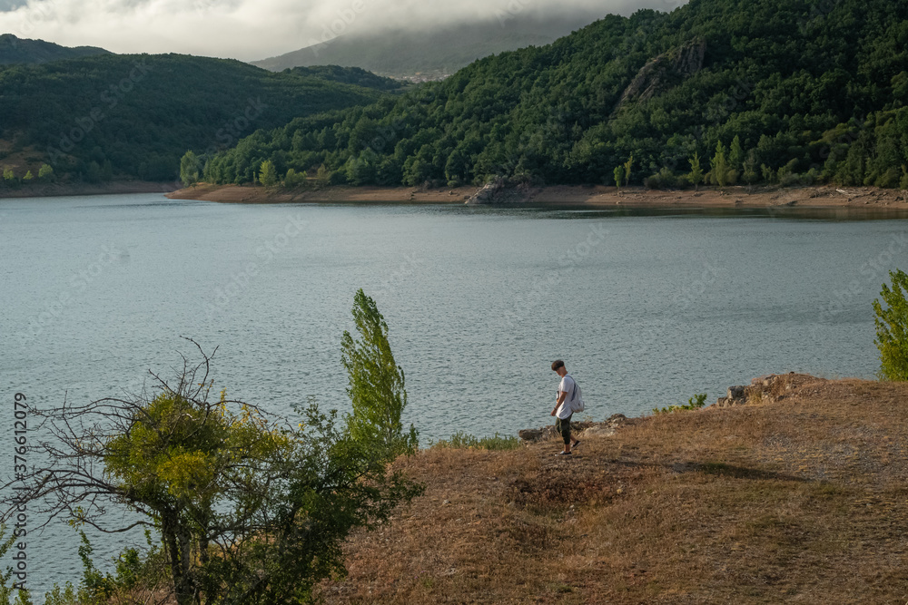 Young teenage man walking alone by the lake Young teenage man walking alone by the lake