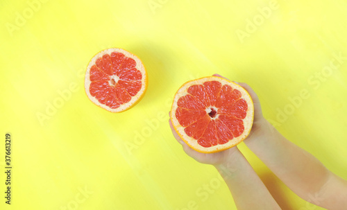 child holds half a grapefruit , yellow background photo