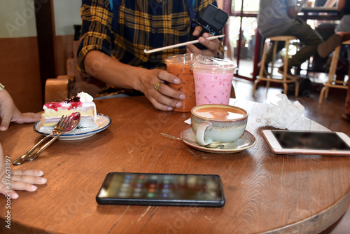 Cup of coffee and cake on the wooden table with smartphone