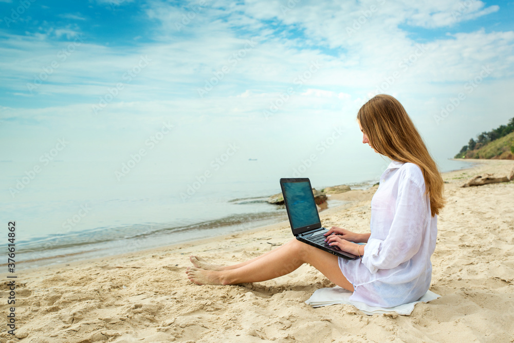 Freelancer workplace on the sea beach. Young woman working travel from outdoor office in nature. Traveler girl with laptop. Successful female business.