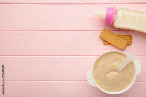 Milk and bowl with porridge for baby on pink background photo