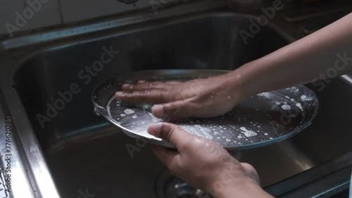Utensils are being cleaned in running tap water inside the kitchen. Indian household and kitchen