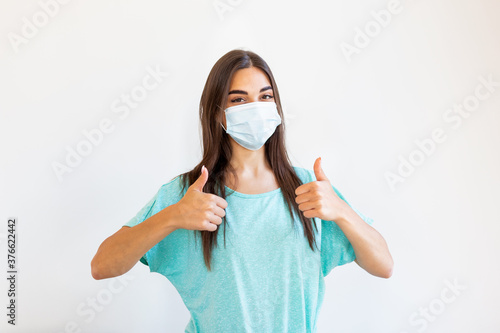 Portrait of young woman wearing face protective mask to prevent Coronavirus and anti-smog. Portrait of young woman wearing face mask. Thumb up.