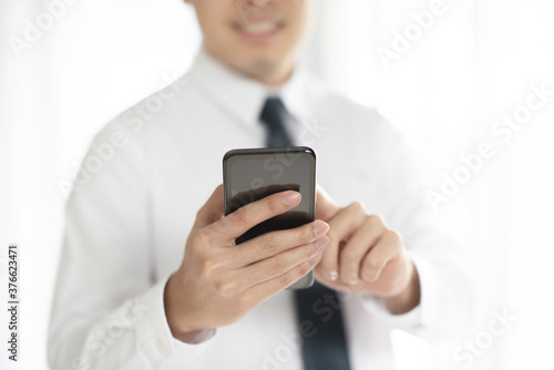 Close up of a businessman using mobile smart phone, background for copy.