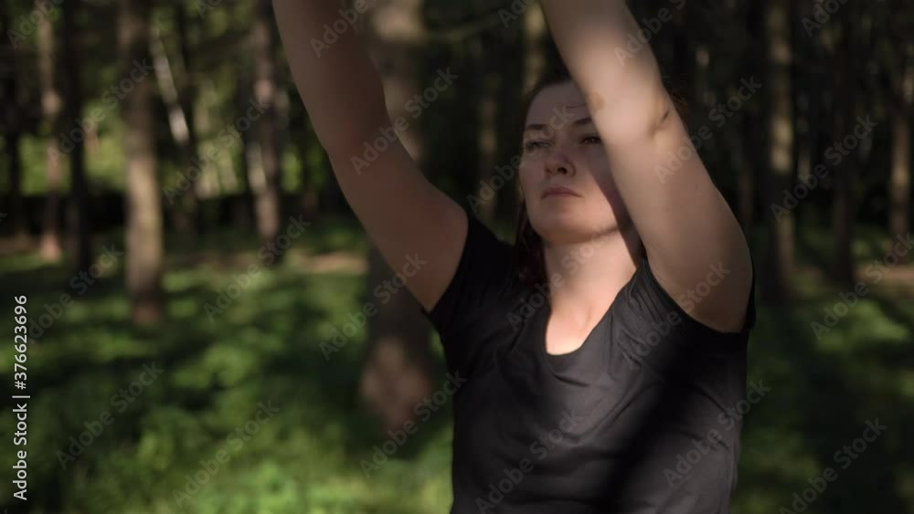 Girl black T-shirt wireless headphones stretches does warm-up gymnastics forest park. Outstretched arms. Workout yoga stretching. Calm relaxing environment. Self-control concentration exercise Girl black T-shirt wireless headphones stretches does warm-up gymnastics forest park. Outstretched arms. Workout yoga stretching. Calm relaxing environment. Self-control concentration exercise