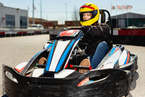 Glad cheerful woman driving sport car for karting in a circuit lap outdoor in sport club