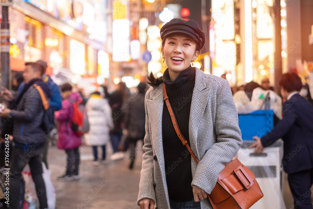 Beautiful smiling woman tourists traveling in walking at street shopping center Shibuya in Tokyo, Japan.