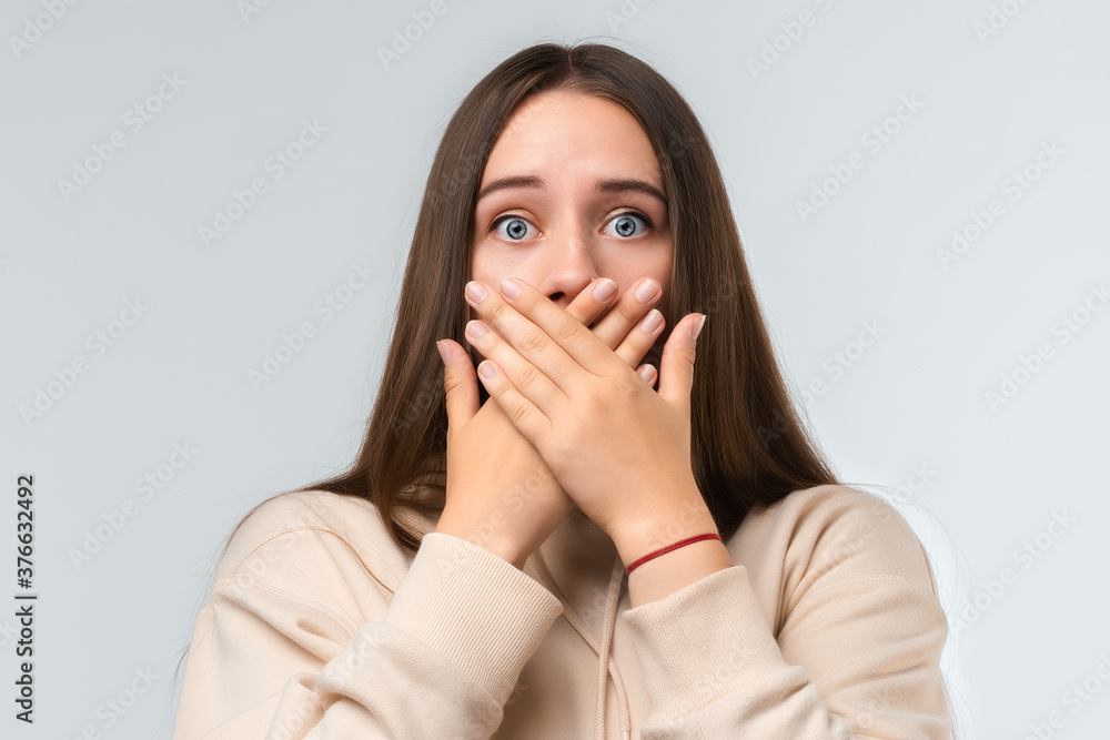 Shocked young woman covering mouth with hands on white background. Keep silence concept Shocked young woman covering mouth with hands on white background. Keep silence concept