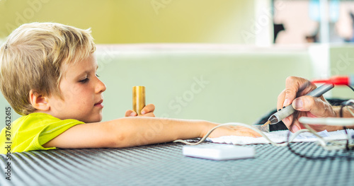 Vegetative rezonans diagnostic. Doctor examines child boy hand with the help of bioresonance dipstick tester, reveal disease causing bacteria via electromagnetic fields based on biofeedback principle