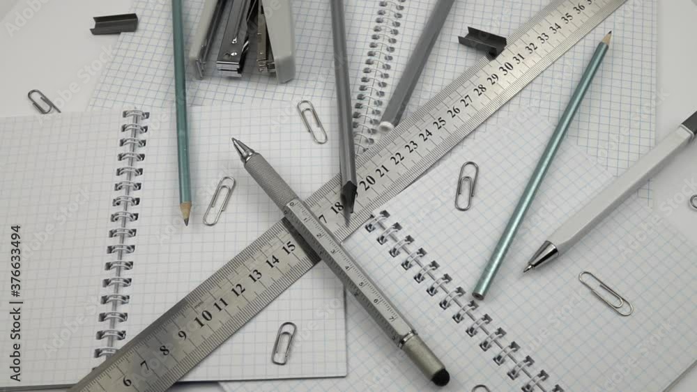 Various stationery in gray are laid out on the different paper notepad, slow motion Various stationery in gray are laid out on the different paper notepad, slow motion