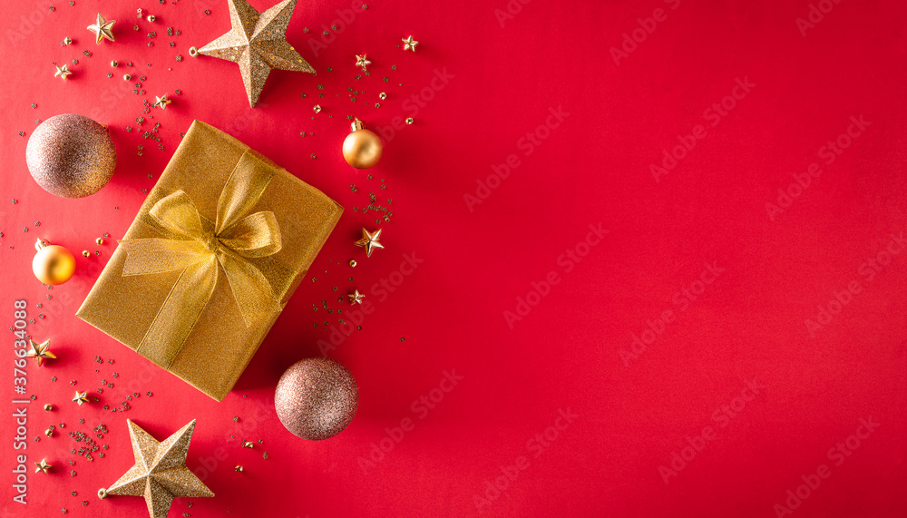 Christmas background decoration concept. Top view of golden gift box with christmas ball and star on red background. Christmas background decoration concept. Top view of golden gift box with christmas ball and star on red background.