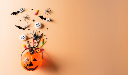 Top view of Halloween crafts, orange pumpkin, ghost, bat and black spider on pastel orange background. Flat lay, top view with copy space for text.