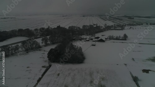 Aerial night flight over snowy landscape winter wonderland moving towards farm buildings also showing snow covered pastures and horizon in further background 4k quality high resolution footage photo