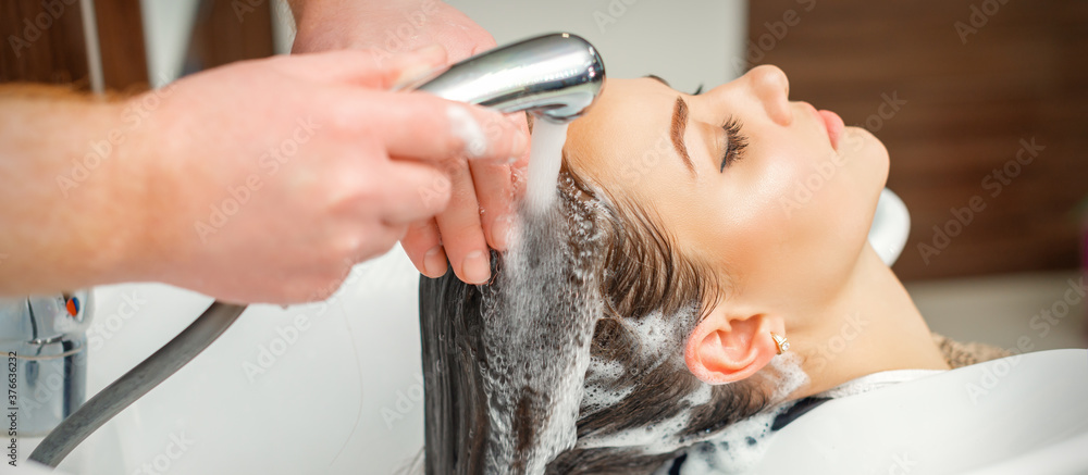 Close up of hands of hairdresser washing hair of woman in sink at beauty salon - obrazy, fototapety, plakaty 
