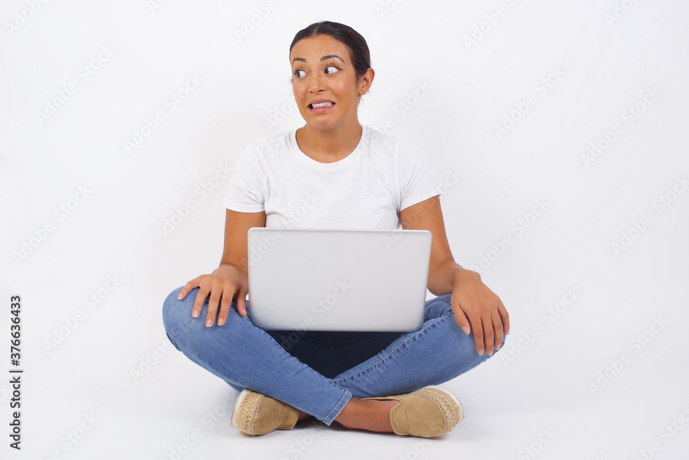 Oops! Portrait of female with specific appearance clenches teeth and looks confusedly aside, realises her bad mistake, poses against copy area for your advertising or promotional background.