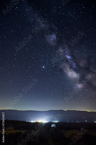 View of the Milky Way over the lights of a mountain village