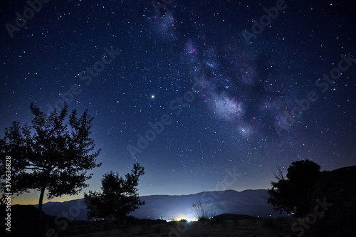 View of the Milky Way over the lights of a mountain village