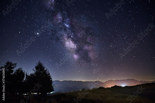 View of the Milky Way over the lights of a mountain village