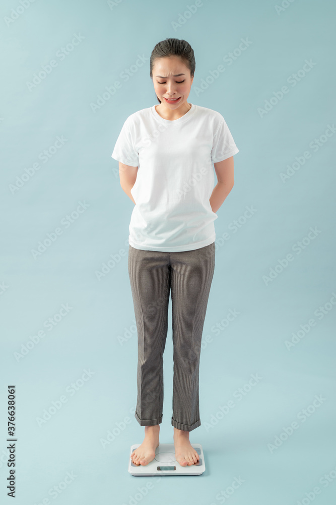 Sad young woman standing on scale. She is not satisfied with the result. Diet and healthy living concept. Sad young woman standing on scale. She is not satisfied with the result. Diet and healthy living concept.
