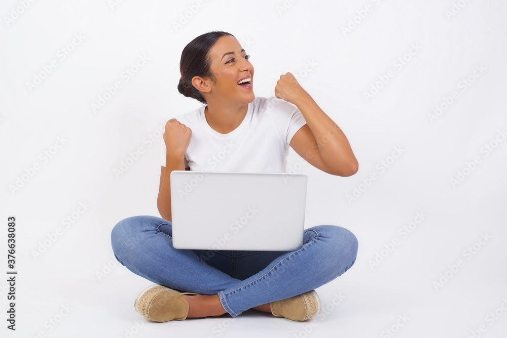 Attractive young caucasian woman celebrating a victory punching the air with her fists and a beaming toothy smile over a white studio background with copy space. Attractive young caucasian woman celebrating a victory punching the air with her fists and a beaming toothy smile over a white studio background with copy space.