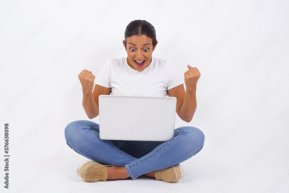 Portrait of beautiful brunette female looks with excitement at camera, keeps hands raised over head, notices something unexpected, isolated over white wall. Lovely woman reacts on sudden news. Portrait of beautiful brunette female looks with excitement at camera, keeps hands raised over head, notices something unexpected, isolated over white wall. Lovely woman reacts on sudden news.