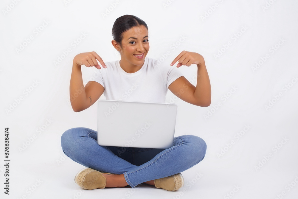 Charming emotive caucasian woman pointing down or at her t-shirt while smiling joyfully and expressing positive emotions over white background. Girl trained a lot, she wants to show her muscles Charming emotive caucasian woman pointing down or at her t-shirt while smiling joyfully and expressing positive emotions over white background. Girl trained a lot, she wants to show her muscles