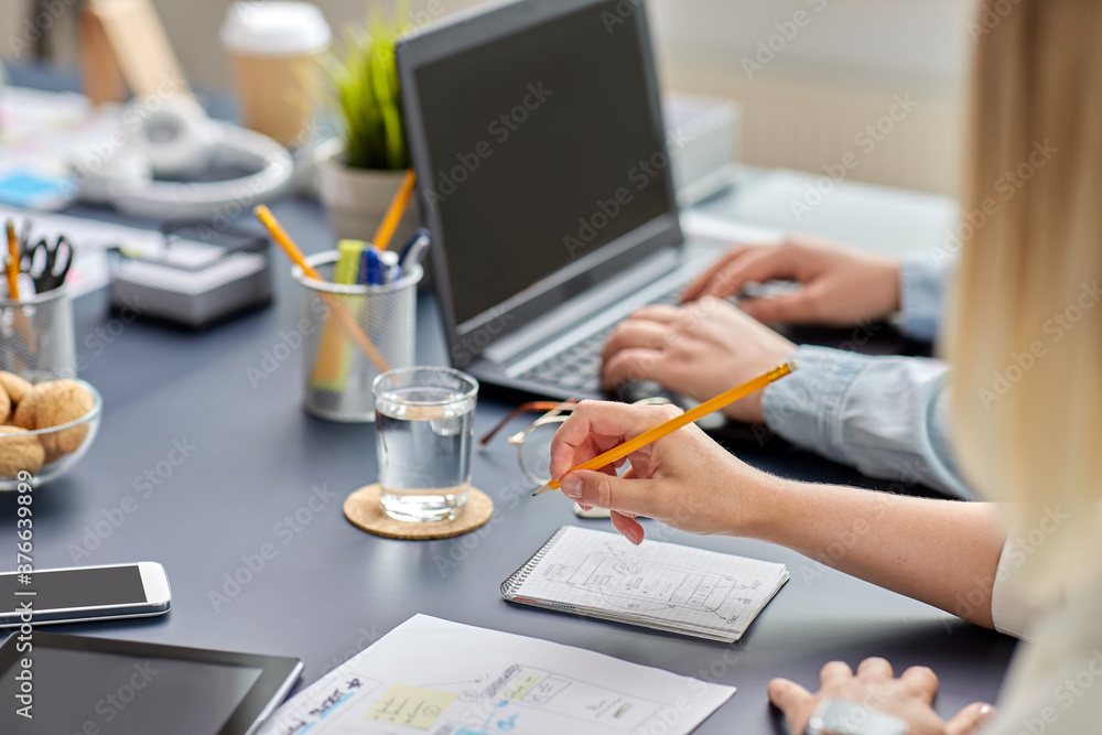 business, people and technology concept - close up of ui designer with notebook and pencil working on mobile app design at office business, people and technology concept - close up of ui designer with notebook and pencil working on mobile app design at office