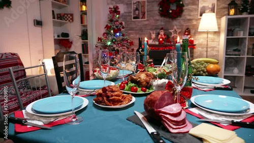 Table with traditional food for christmas celebration. Candles for x mas gathering. Xmas celebration in decorated room full of globe decorations and christmas tree with fireplace, big festive dinner photo