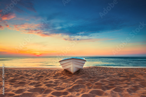 Fototapeta Naklejka Na Ścianę i Meble -  Tropical Seascape with a boat on sandy beach at cloudy sunrise or sunset