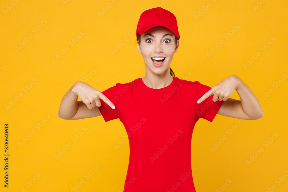 Delivery employee woman in red cap pointing fingers on blank t-shirt uniform workwear work courier in service during quarantine coronavirus covid-19 virus isolated on yellow background studio portrait Delivery employee woman in red cap pointing fingers on blank t-shirt uniform workwear work courier in service during quarantine coronavirus covid-19 virus isolated on yellow background studio portrait