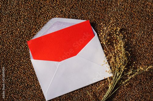 white envelope and red letter with dried grass for greeting mockup seasonal concepts on wool fabric background