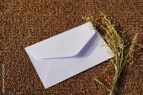 white envelope with dried grass for greeting mockup seasonal concepts on wool fabric background