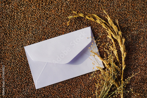 white envelope with dried grass for greeting mockup seasonal concepts on wool fabric background