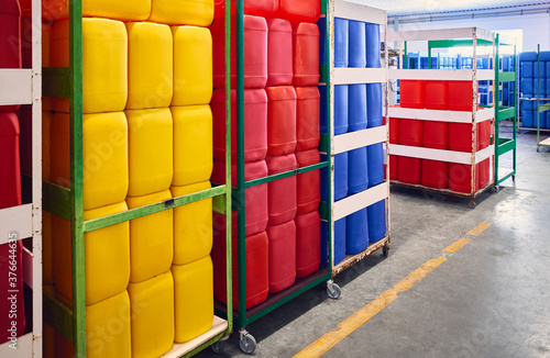 Red, yellow and blue plastic containers for chemicals in a warehouse.