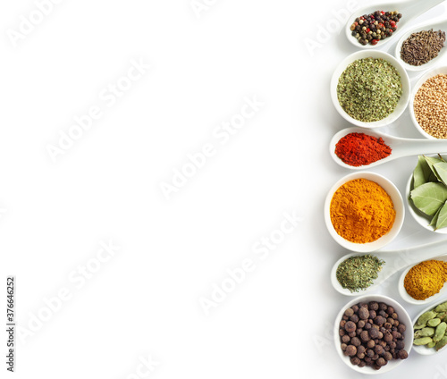Top view of various spices in bowls and spoons isolated on white background. Copy space.