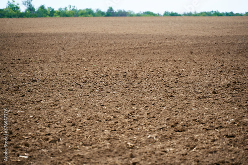 plowed field and blue sky, soil and clouds of a bright sunny day - concept of ag Fototapet