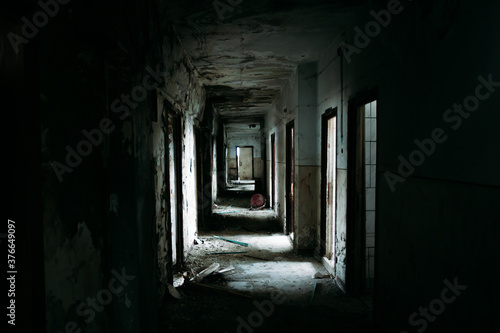 Eerie atmosphere in an abandoned building with huge windows and spider webs and one lamp. Halloween themed image. 