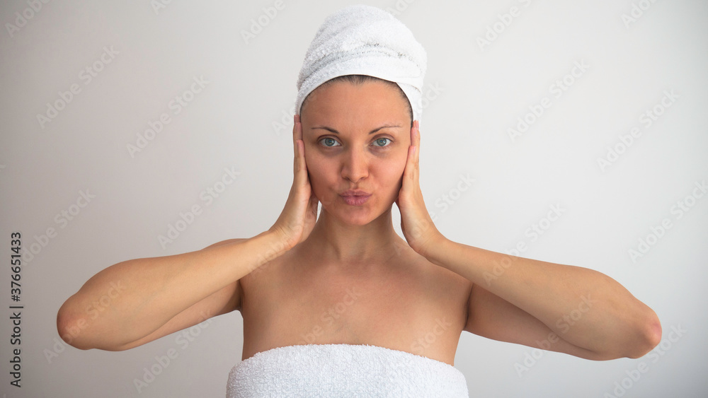 Caucasian woman without makeup with wrapped body and hair in white towels. Caucasian woman without makeup with wrapped body and hair in white towels.