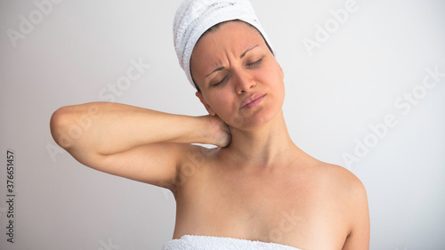 Woman wrapped in a white towel with neck pain. Negative space or copy space for text.