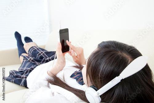 携帯電話で音楽を聴く女子高校生